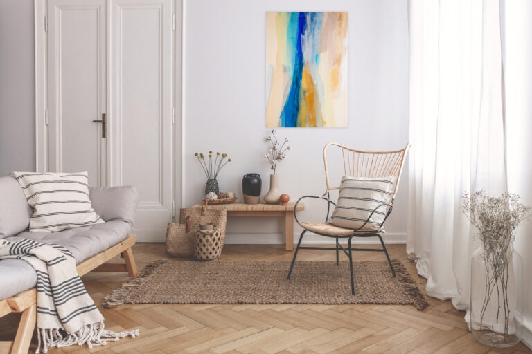 Armchair on rug next to bench with plants in white loft interior with wooden sofa. Real photo